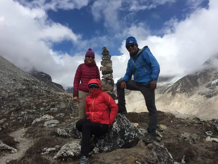 Three trekkers resting beside a cairn on a high ridge