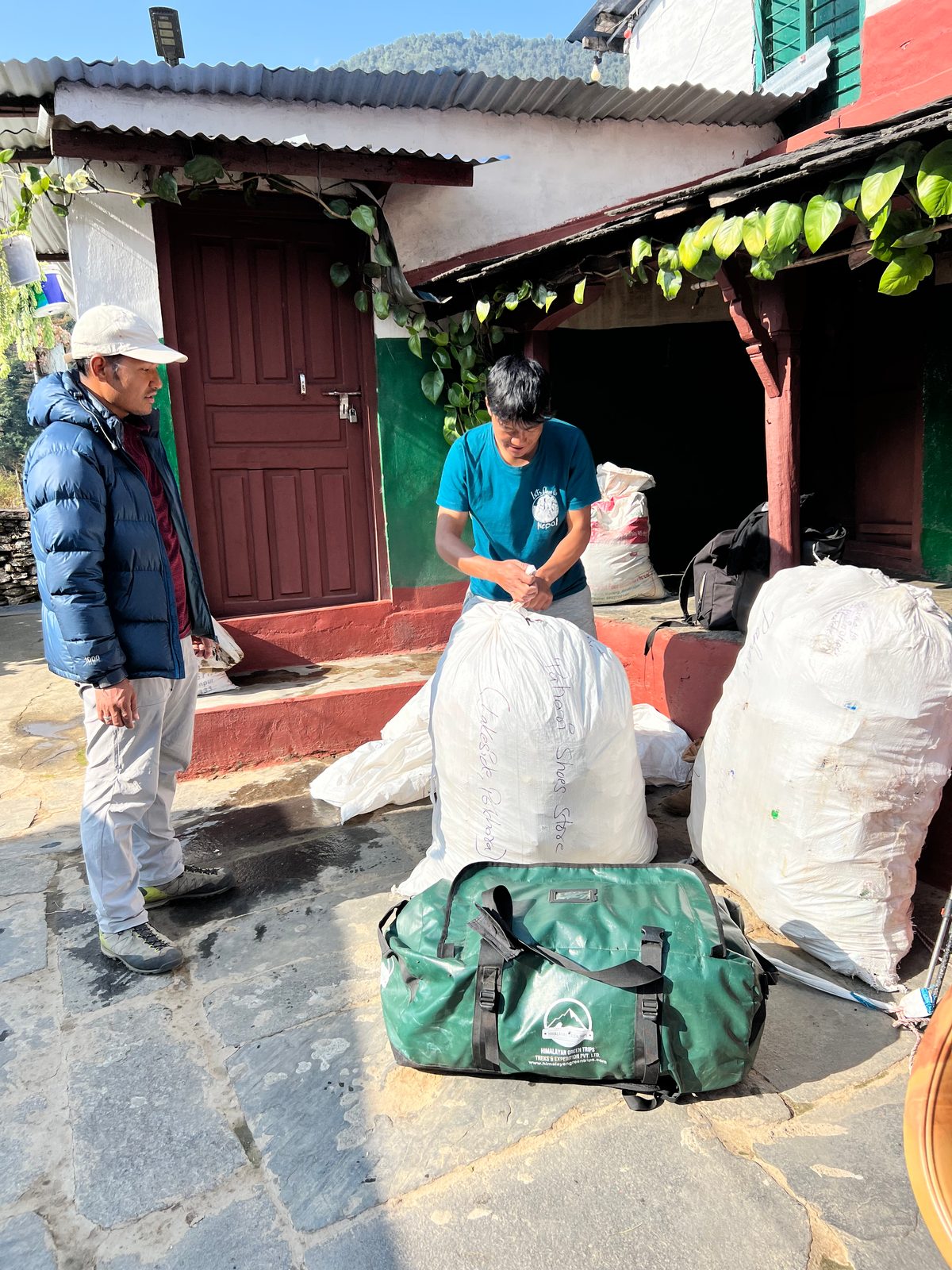 Two people packing sacks and trekking bags outside a building